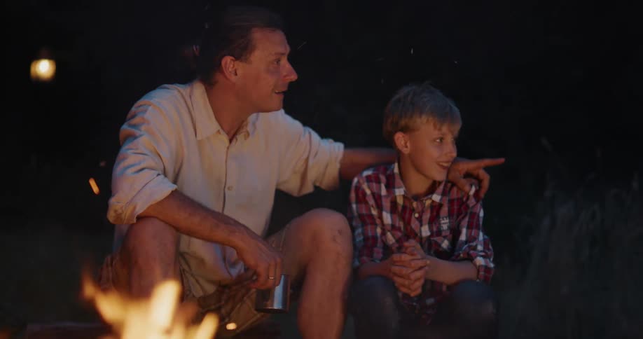 Father and son are sitting by a bonfire together