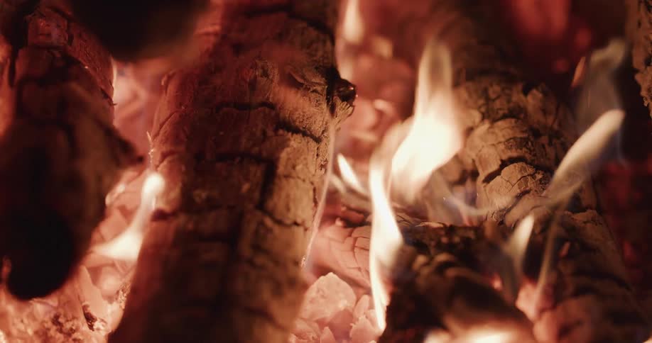 Flames wave in the breeze as the wood of a campfire burns