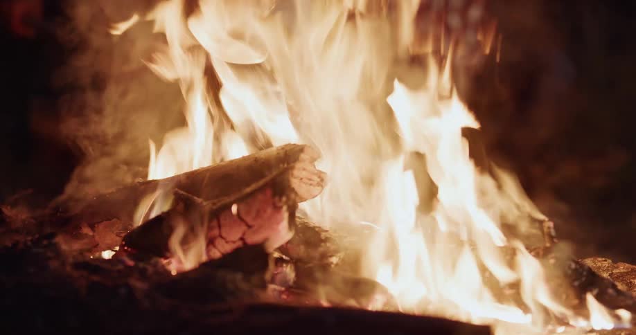 A person is putting more logs on a bonfire