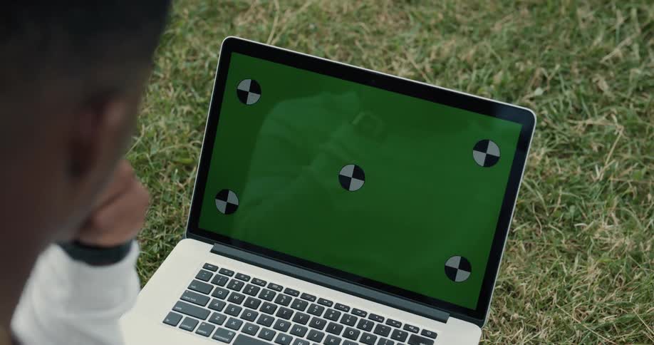 A man is sitting outdoors with his laptop