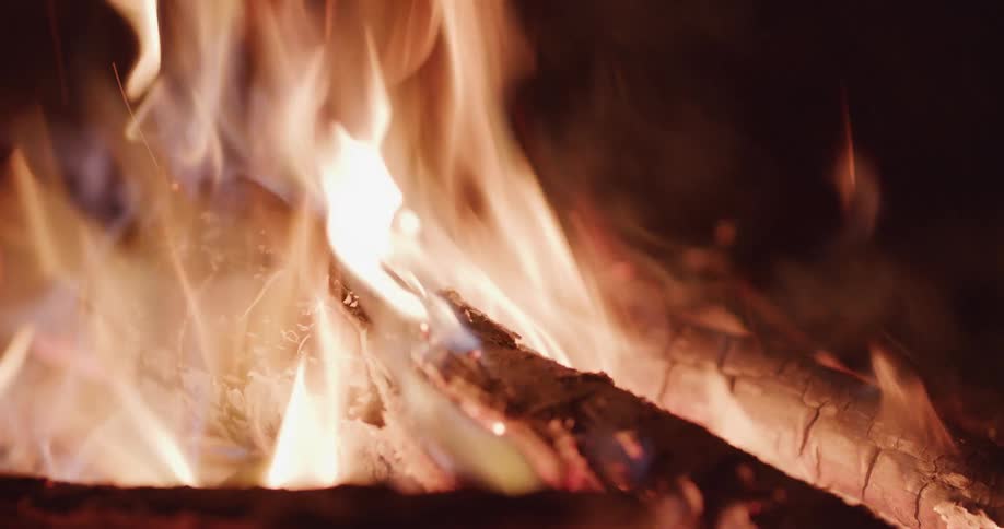 Flames wave in the breeze as the wood of a campfire burns