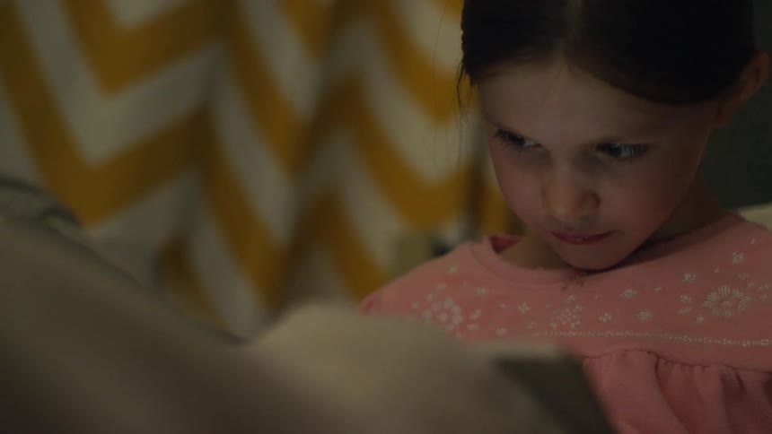 A girl looks down at a tablet