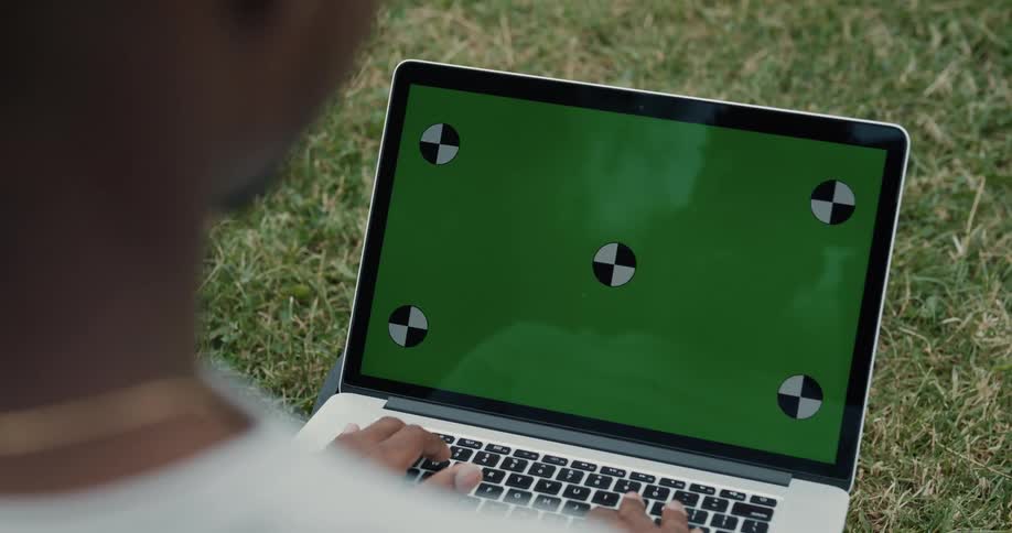 A man is sitting outdoors and browsing on his laptop
