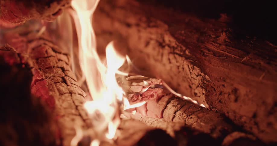 Flames wave in the breeze as the wood of a campfire burns