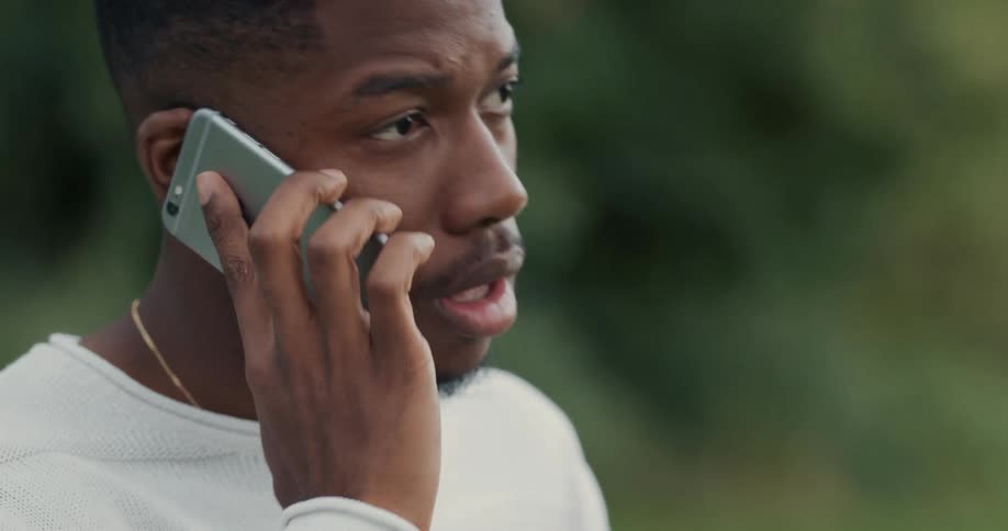 A man looks upset as he answers the phone outside