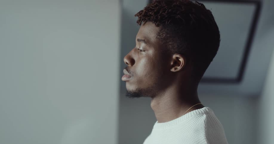 Thoughtful black man standing indoors drinking a cup of coffee