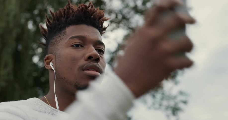 A man is sitting outdoors and wearing headphones
