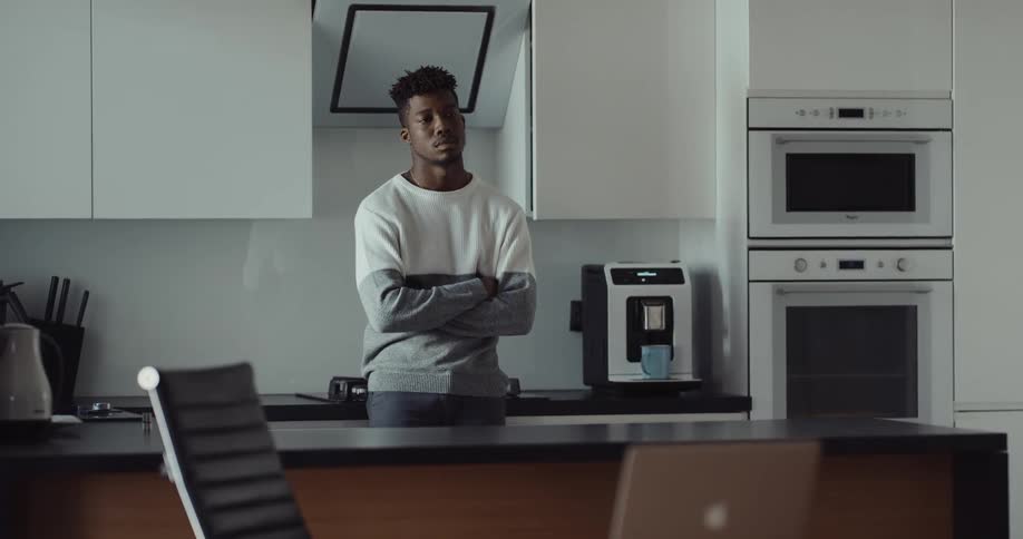 A man is standing in his kitchen during the day time