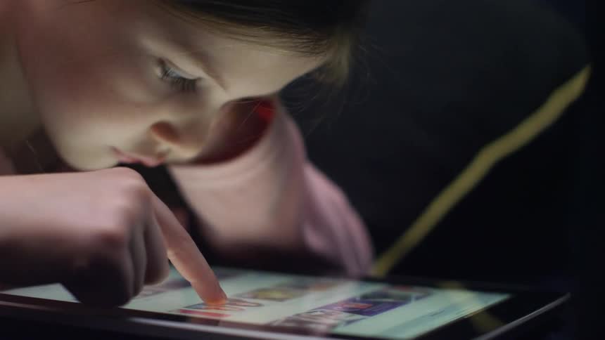 A girl scrolls on a tablet