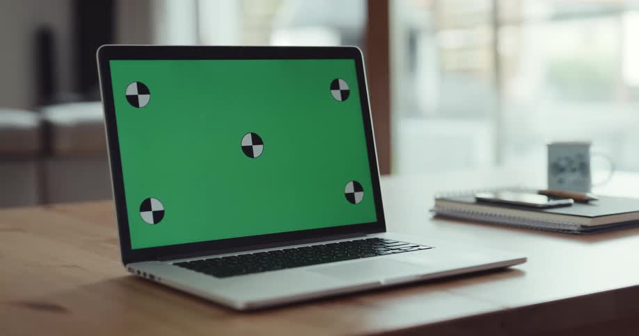 Silver laptop on table next to notebook and cup
