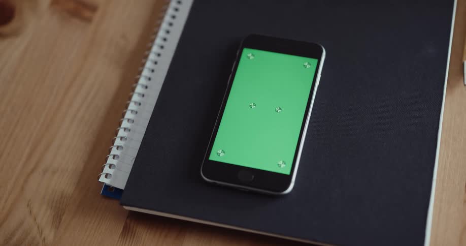 Picking up cell phone lying on blue binder from wood table