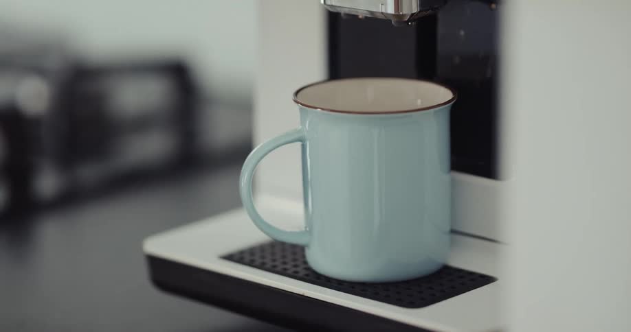 A person puts their coffee cup on the machine and presses a button