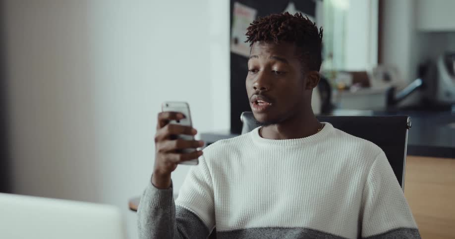 A man is talking on his cellphone and sitting in a chair