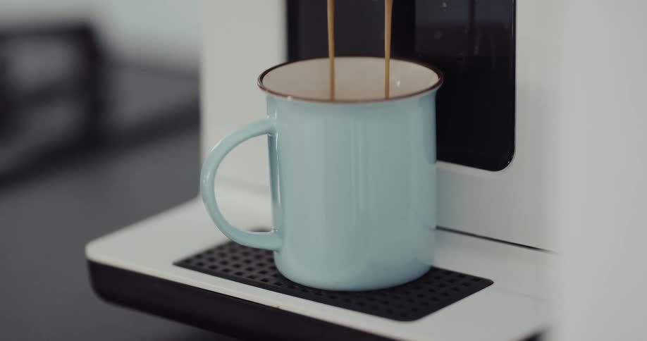 Coffee dripping from coffee machine into a blue enamel mug