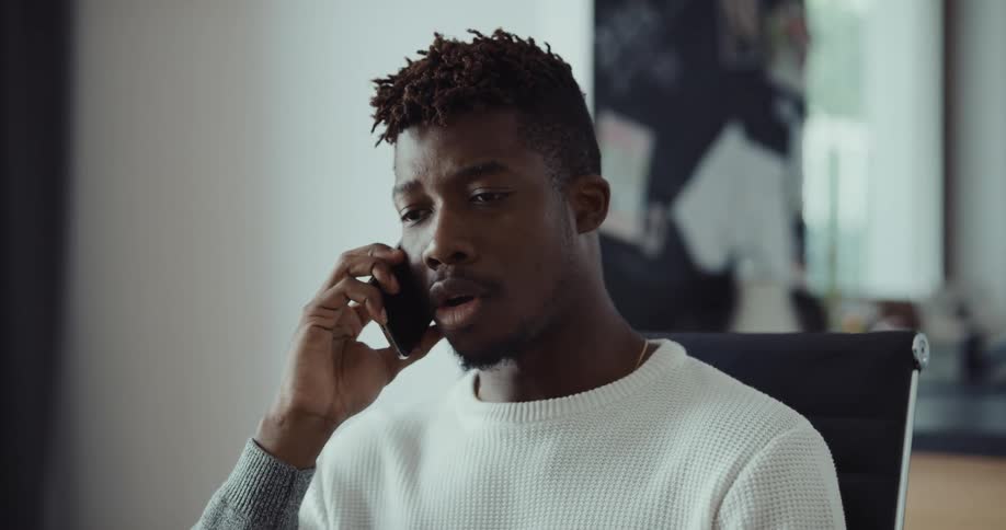 A man is sitting in a chair and talking on a cellphone