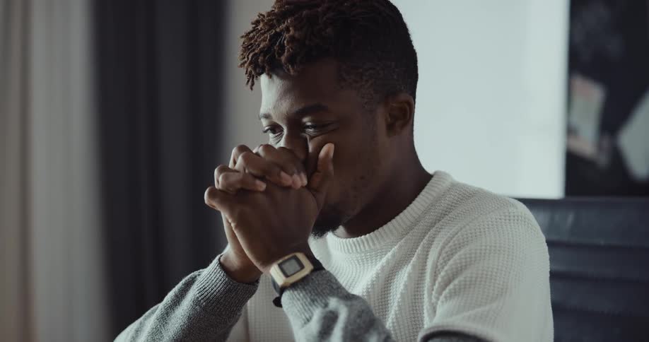 A man puts his hands to his face as he sighs then goes back to his laptop