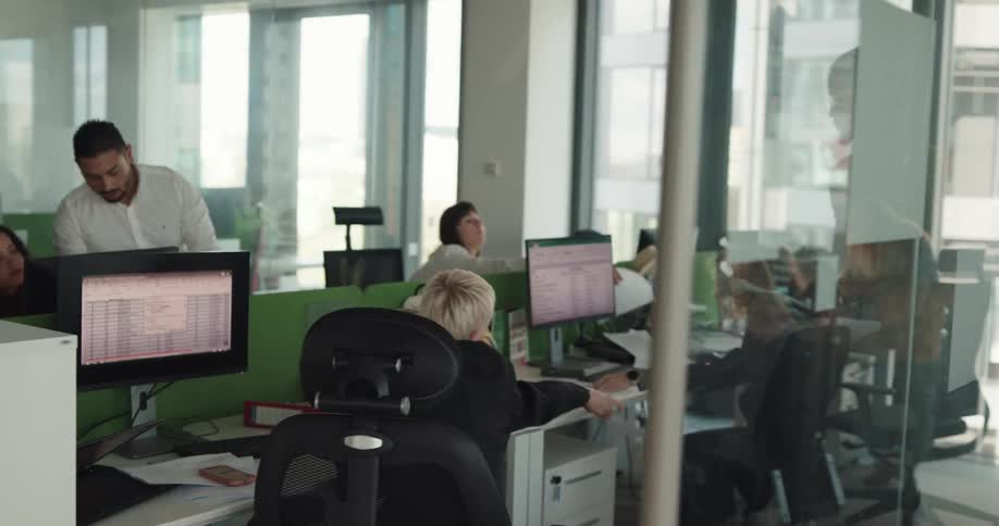Office worker walks into office and takes papers from desk mate