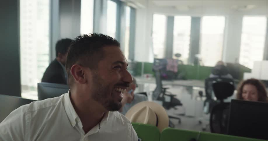 A man smiles and laughs with coworkers as he gestures with the papers hes holding