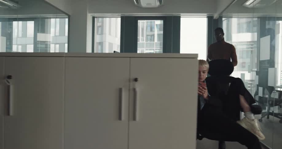 Some coworkers sit in office working while others take a break at their desks