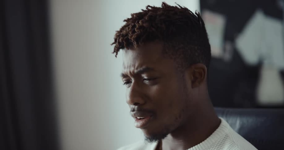 A man is talking on his phone and sitting indoors