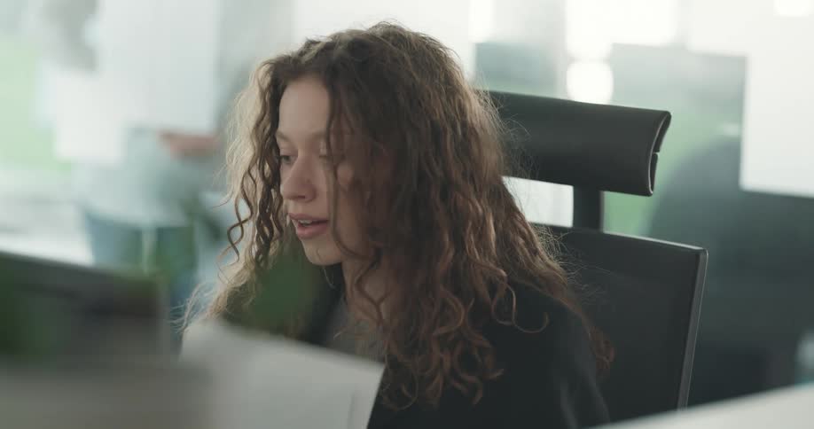 Women sits down at desk in office and starts working