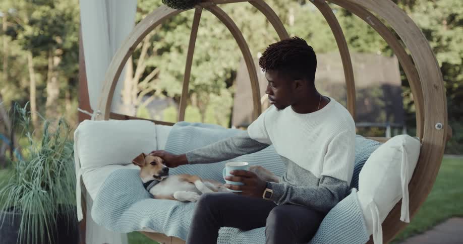 A man is sitting outdoors and petting his dog