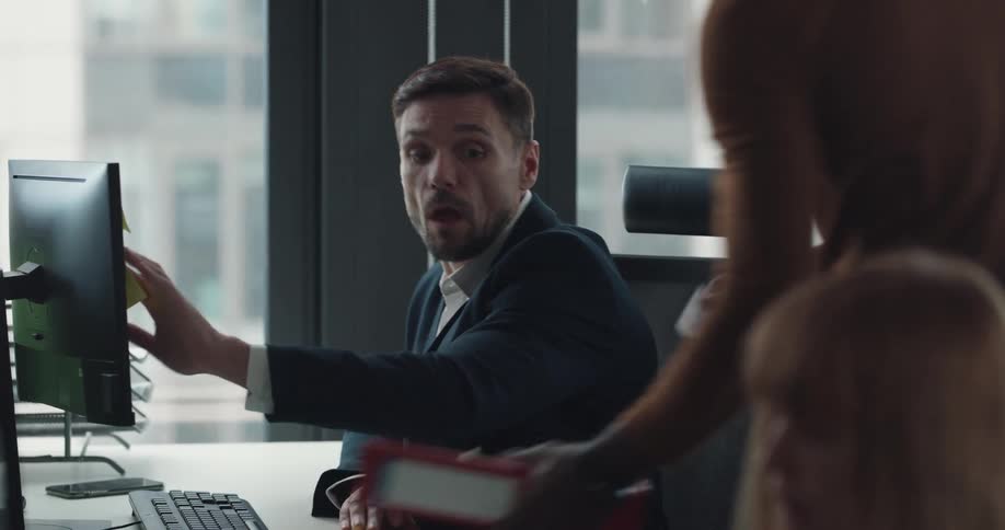A man writes on a sticky note and attaches it to his desk