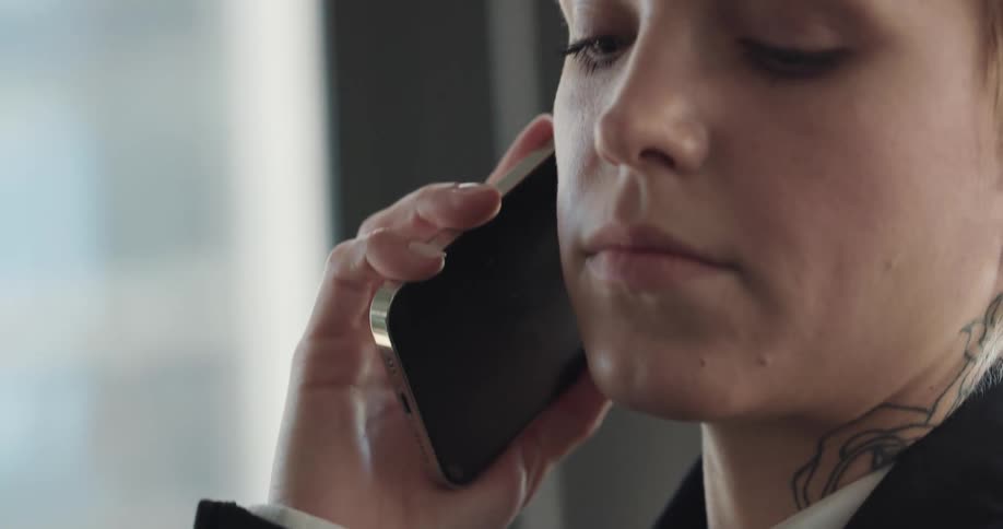 A woman is standing in her office and talking on a cellphone