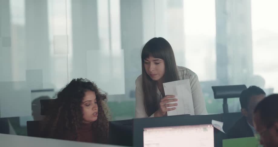 People working on the cubicles of an office talking about tasks