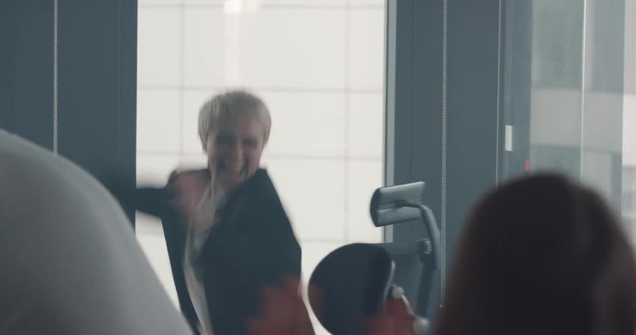 Coworkers watch as fellow employee stands and celebrates after viewing computer monitor