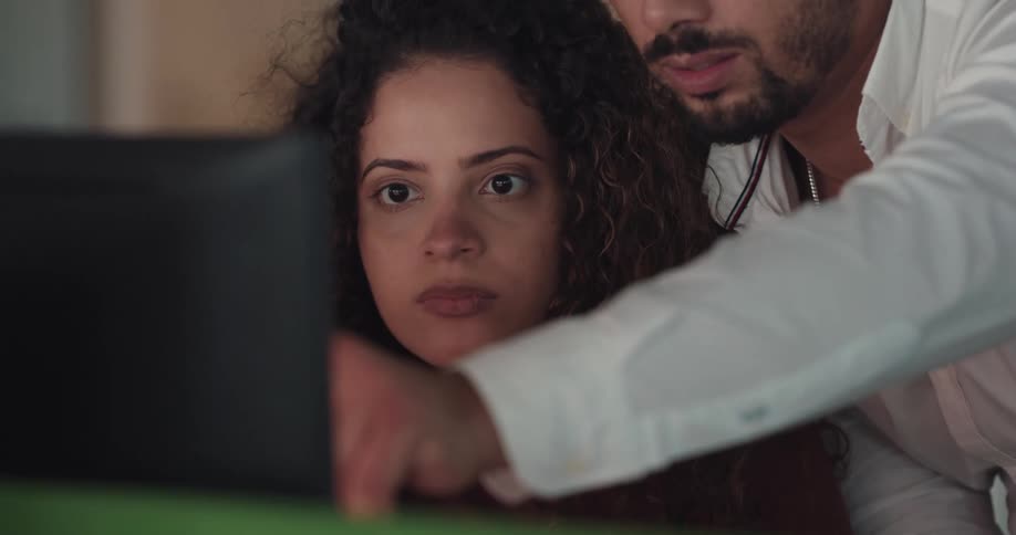 Man helping a female coworker on a task on the computer in the offifce