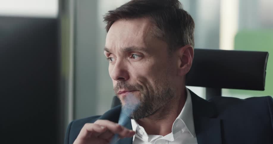 A bored man fidgets with a pen in his hand while sitting in an office during the day