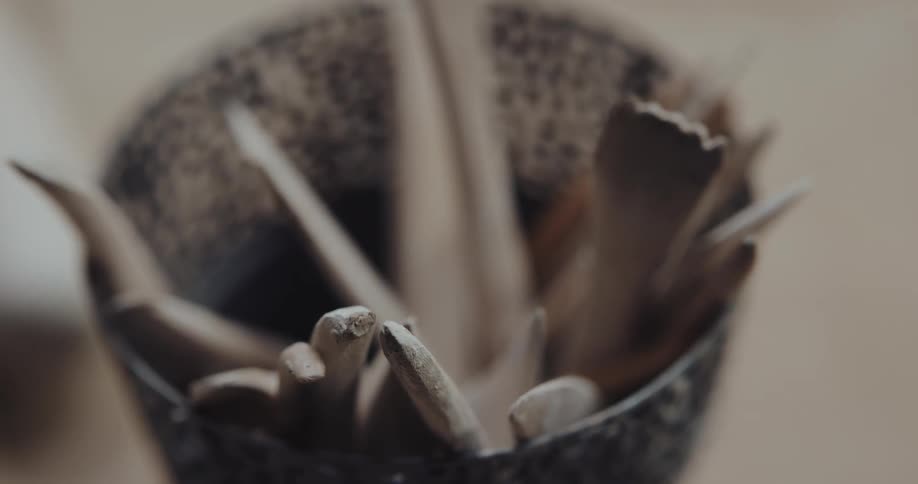 Sculptor picking up pottery wooden tools from a bowl