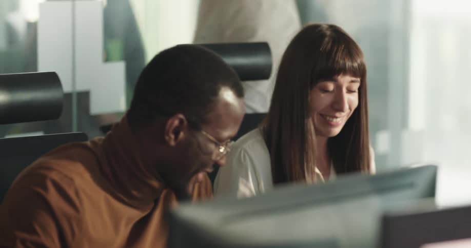 Colleagues chat at their desks in an open concept office