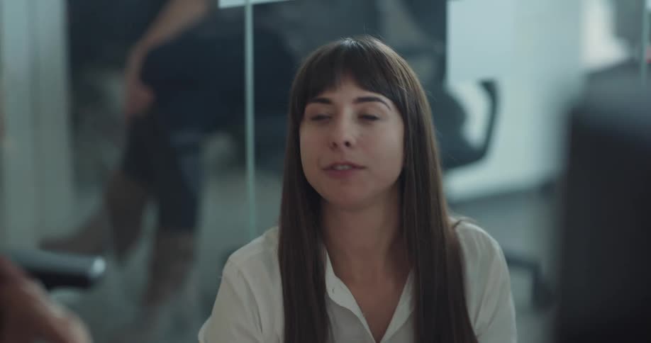Young woman using her smartphone and talking to her coworkers in the office