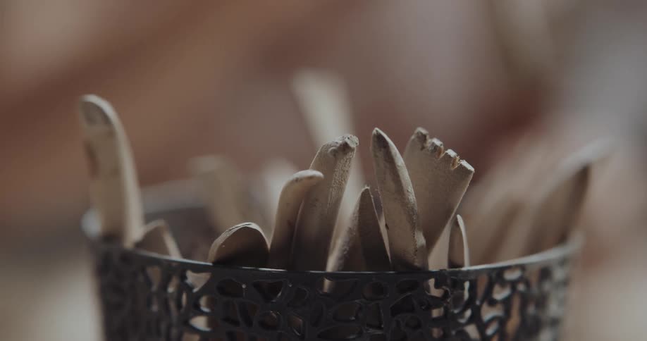 A person grabs for wooden tools out of a cup