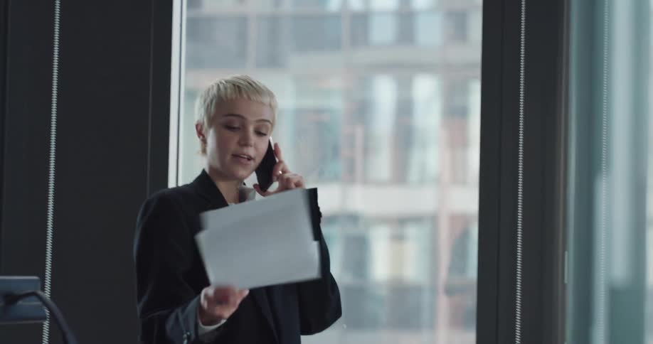 A woman is talking on her phone and standing in her office