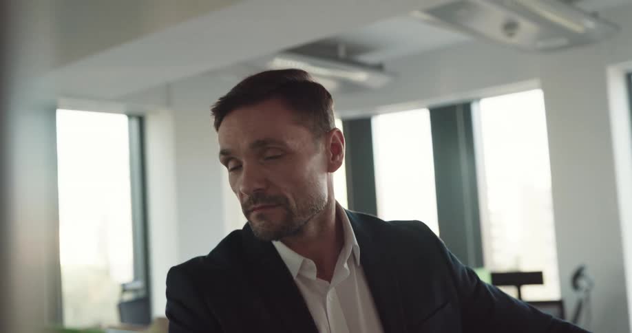A man is sitting in his office and is smiling