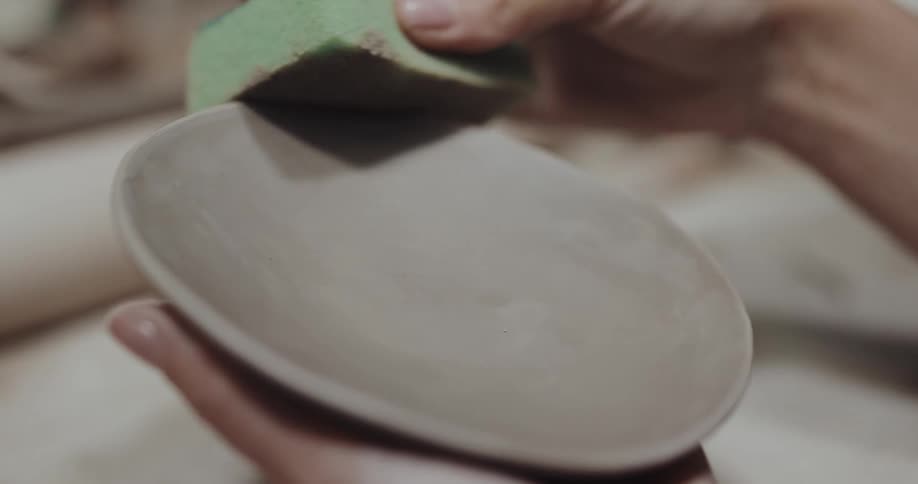 One potter helps another form and shape a clay dish