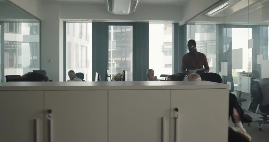 Businesspeople sitting at desks and walking around work at the office