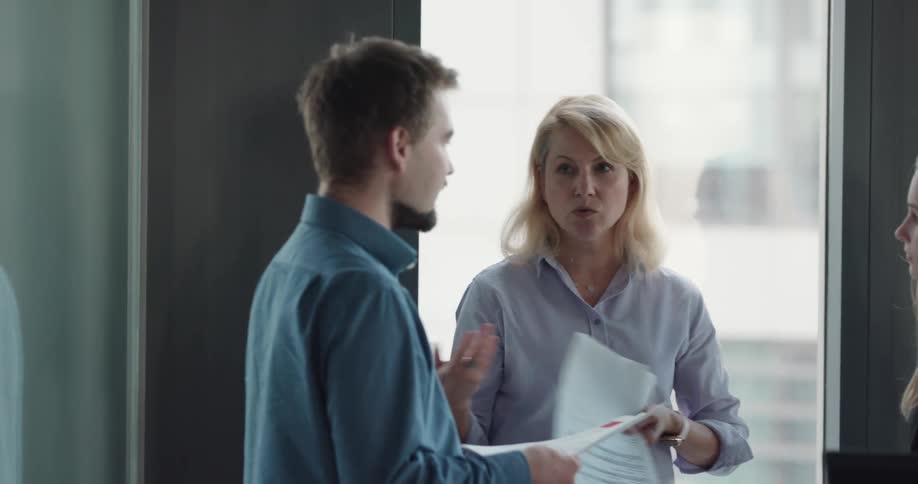 Three coworkers are talking to each other in a room