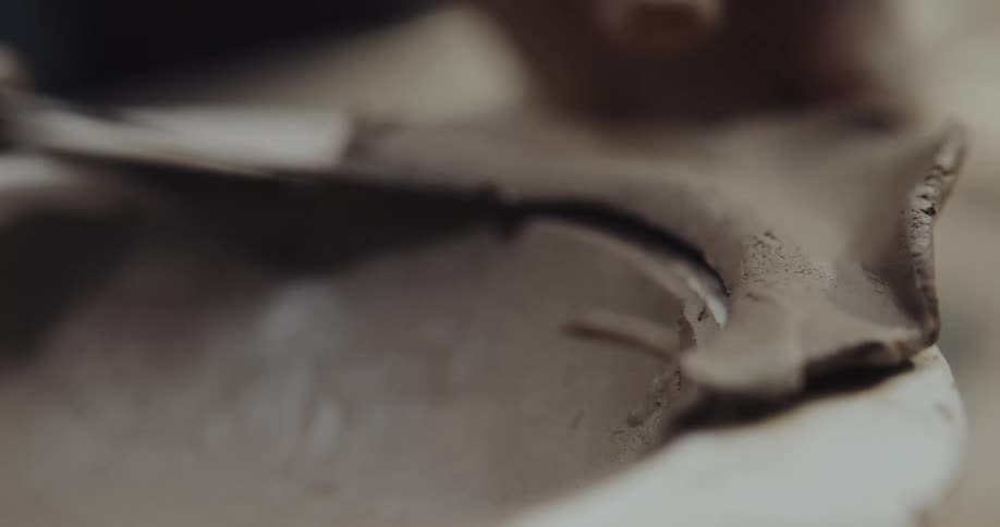 A person is trimming the clay