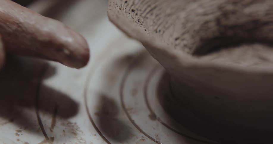 Potter shapes clay bowl on pottery wheel