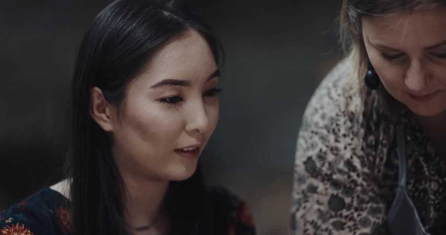 Two women discuss the sculpting of a bowl