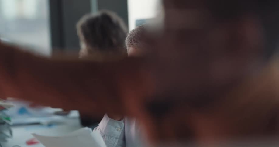 Middle aged man sitting at his shared desk in the office looking through some papers and nodding his head in disbelief