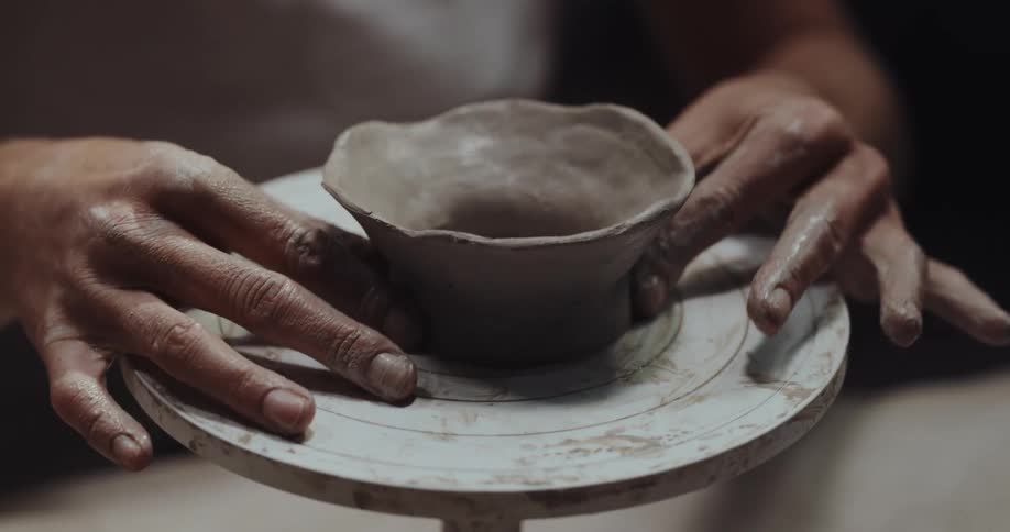 A person is making a bowl out of pottery clay