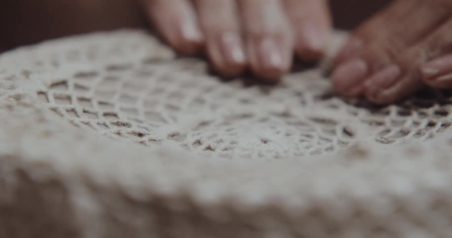Potter adds impression to clay plate using doily