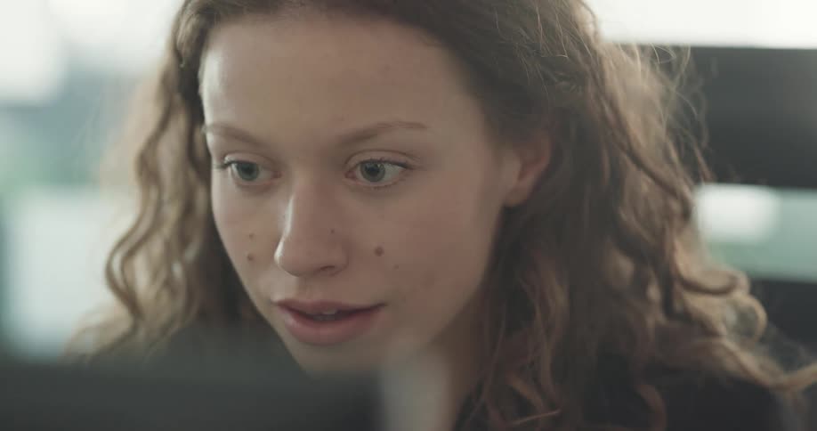 Businesswoman with curly hair sits at desk using computer at the office