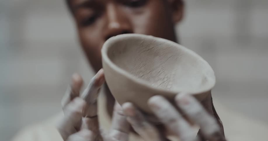 Young black man with dirty hands handling the pottery he is making with clay