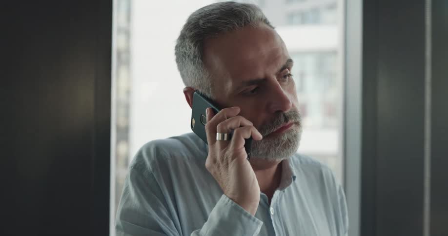 A man is talking on his cellphone while standing in his office